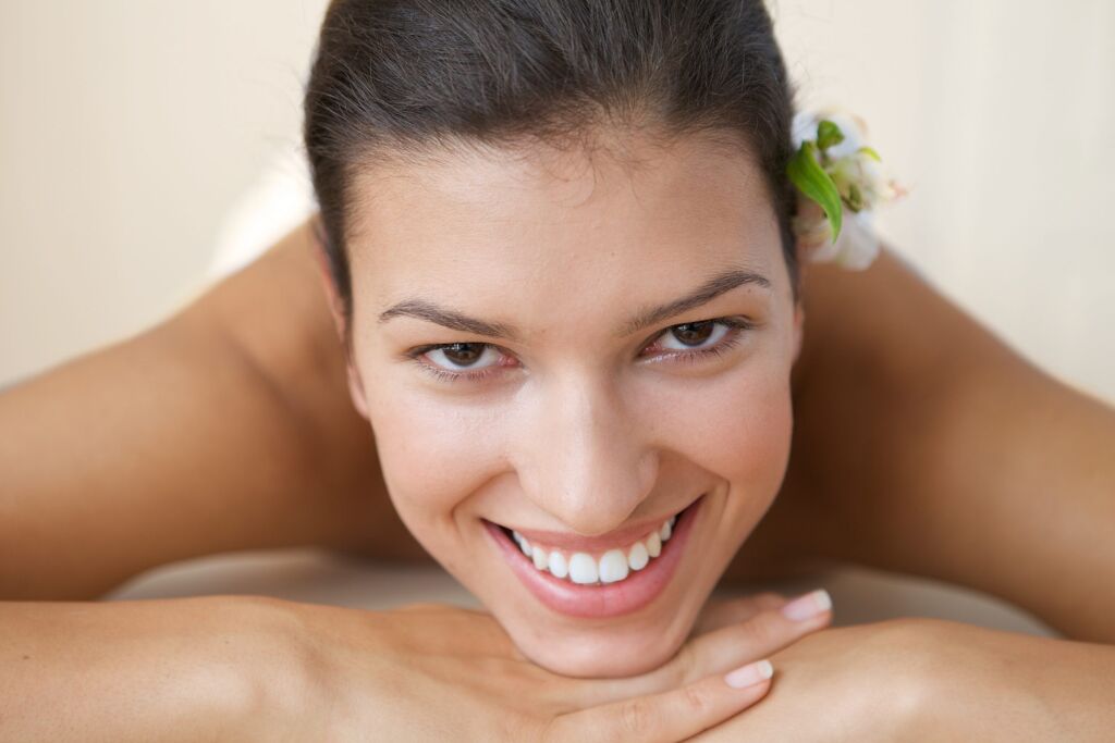 women with young skin smiling and lying on massage table