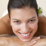 women with young skin smiling and lying on massage table