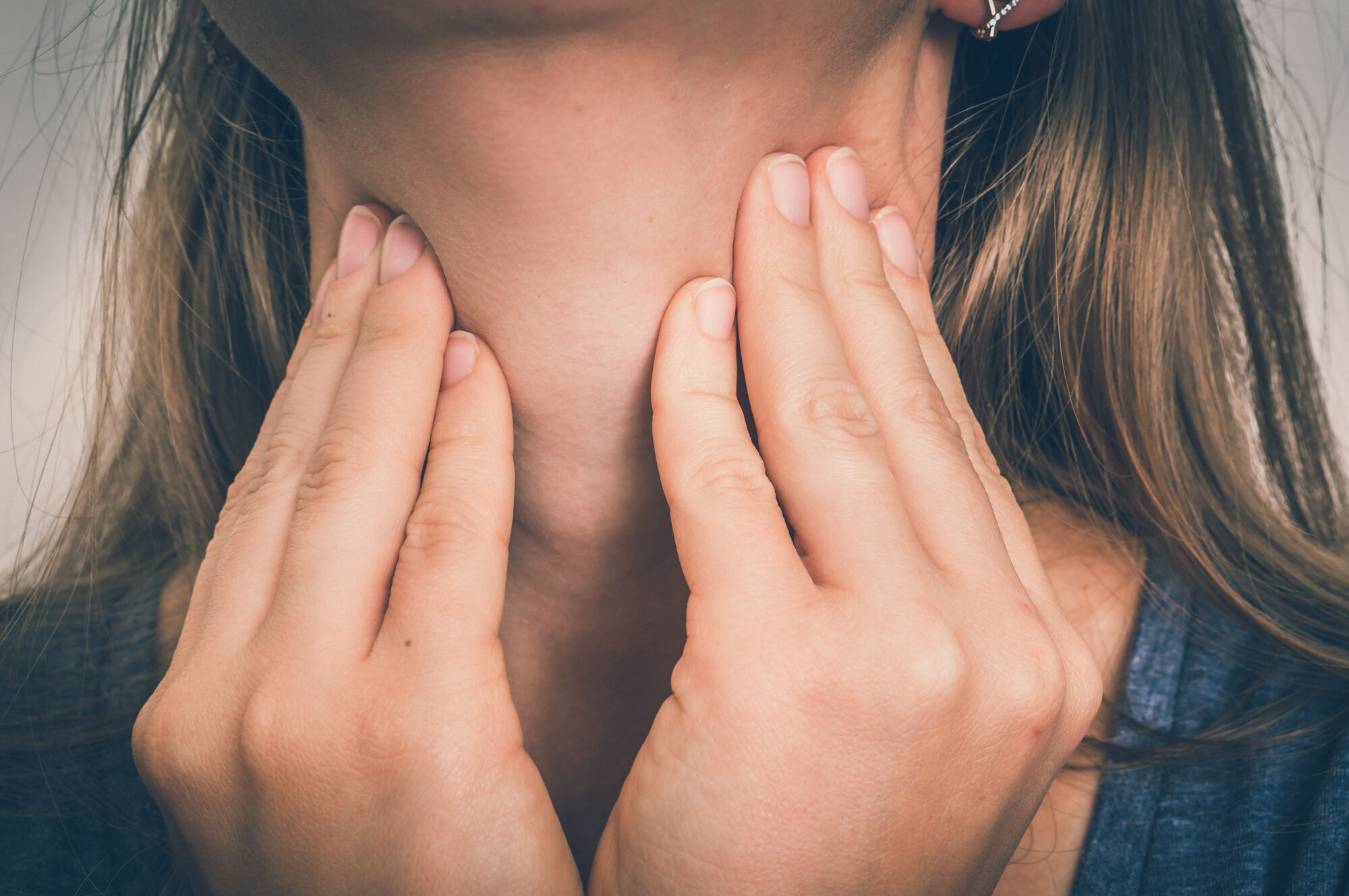 Woman with throat sore is holding her aching throat - body pain concept - retro style